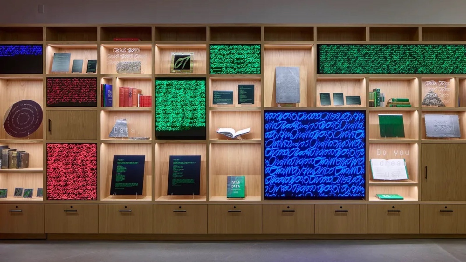 A curated grid of illuminated artwork panels and books from Google's art collection.