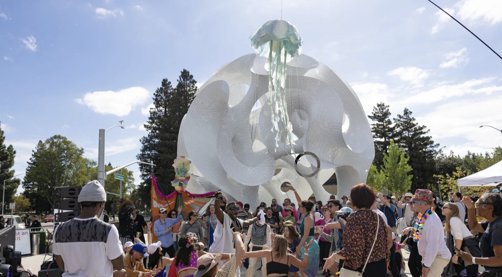 A crowd dancing beneath a large white sculptural pavilion at a Google public activation.